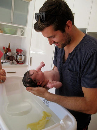 Father bathing a newborn baby