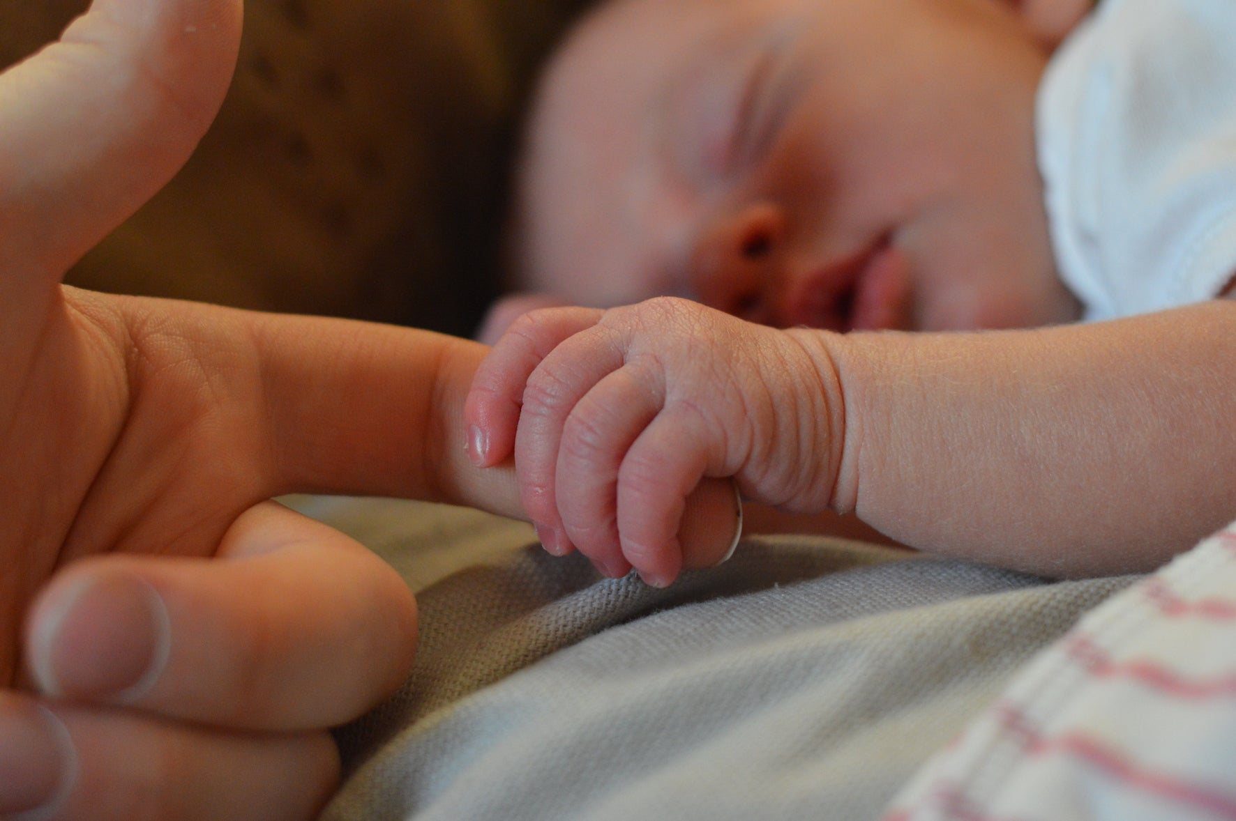 small baby holding hands with mother